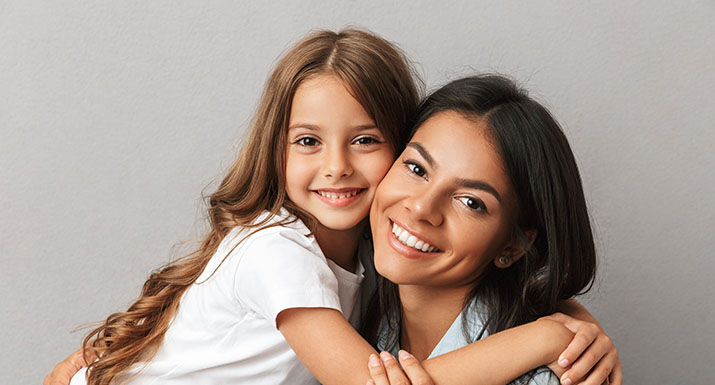 Imagen madre e hija sonriendo para introducir post ¿Qué es y cómo tratar la anquilosis dental?