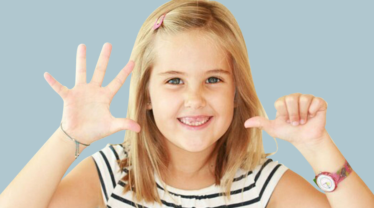 Primer pla d'una nena mostrant amb els seus dits que l'ortodòncia en nens és recomanable als 6 anys